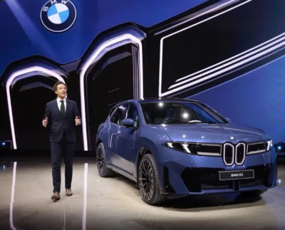 Front fascia of the 2026 BMW iX3 showcasing new Neue Klasse design and 400 kW charging capability. Side profile of the BMW iX3 50 xDrive unveiled at the Japan Mobility Show 2025 with aerodynamic lines and modern styling.