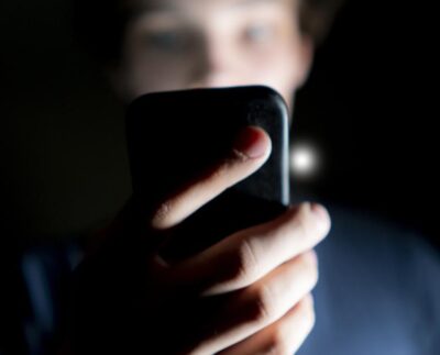 Google issues new warning for all smartphone users about porn-related risks. Smartphone screen showing Google security alert on explicit content ban. Deepfake pornography warning displayed on Android phone. User reading Google Play Store policy update on adult content restrictions. Google removing malicious porn apps from Play Store for user safety. Cybersecurity alert highlighting risks of malware in adult apps. Illustration of smartphone user enabling SafeSearch to block explicit content.