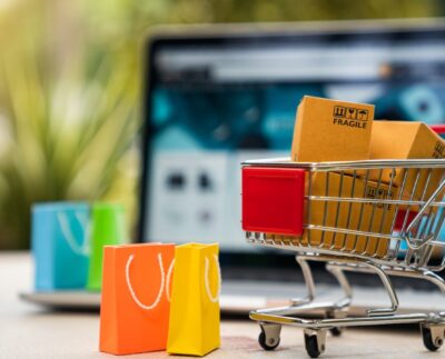 AI-powered online shopping interface showing personalized recommendations. Major online marketplace competing with direct-to-consumer brand websites. Delivery driver preparing same-day shipping packages. Secure online checkout page with encrypted payment options. Shopper browsing products through social media shopping features. Customer using augmented reality to preview products at home. Modern e-commerce warehouse with automated technology.